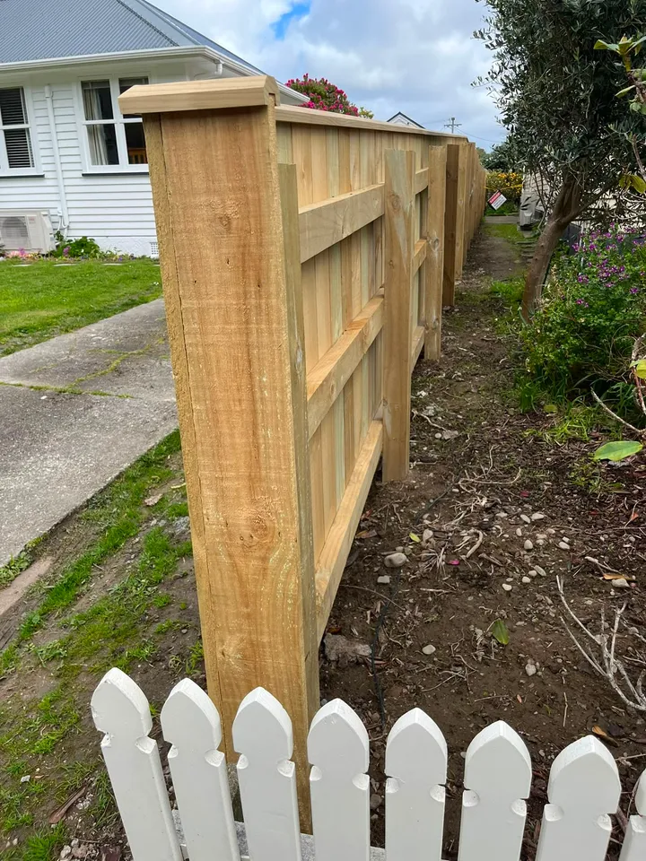 Timber post-and-panel fence beside a white picket fence