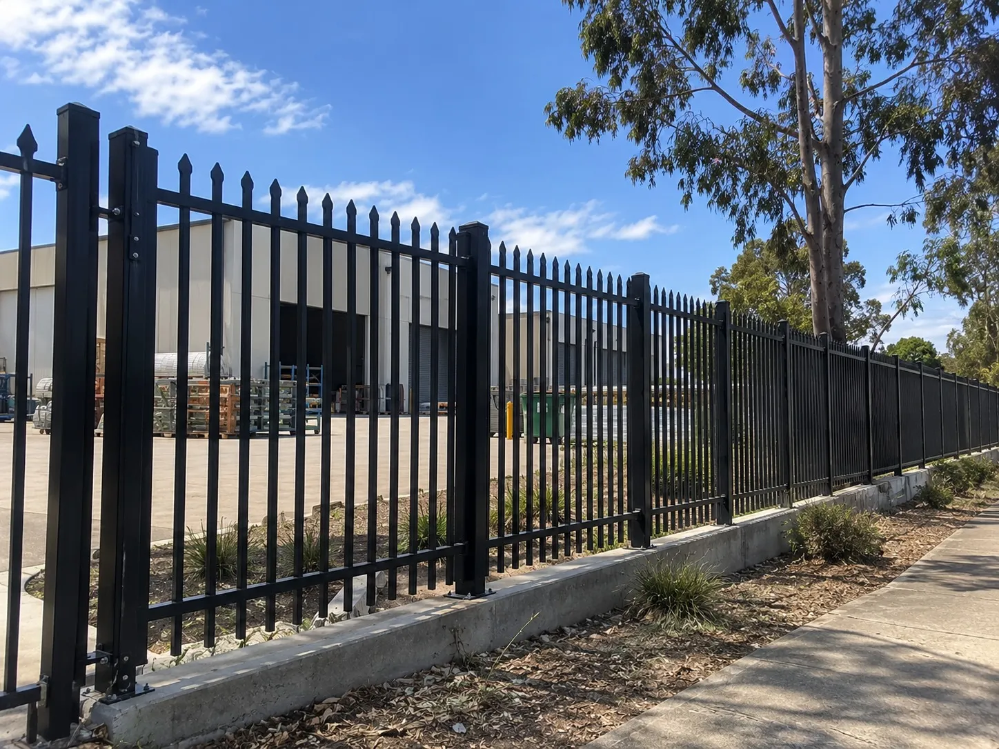 Black steel palisade security fence around an industrial yard